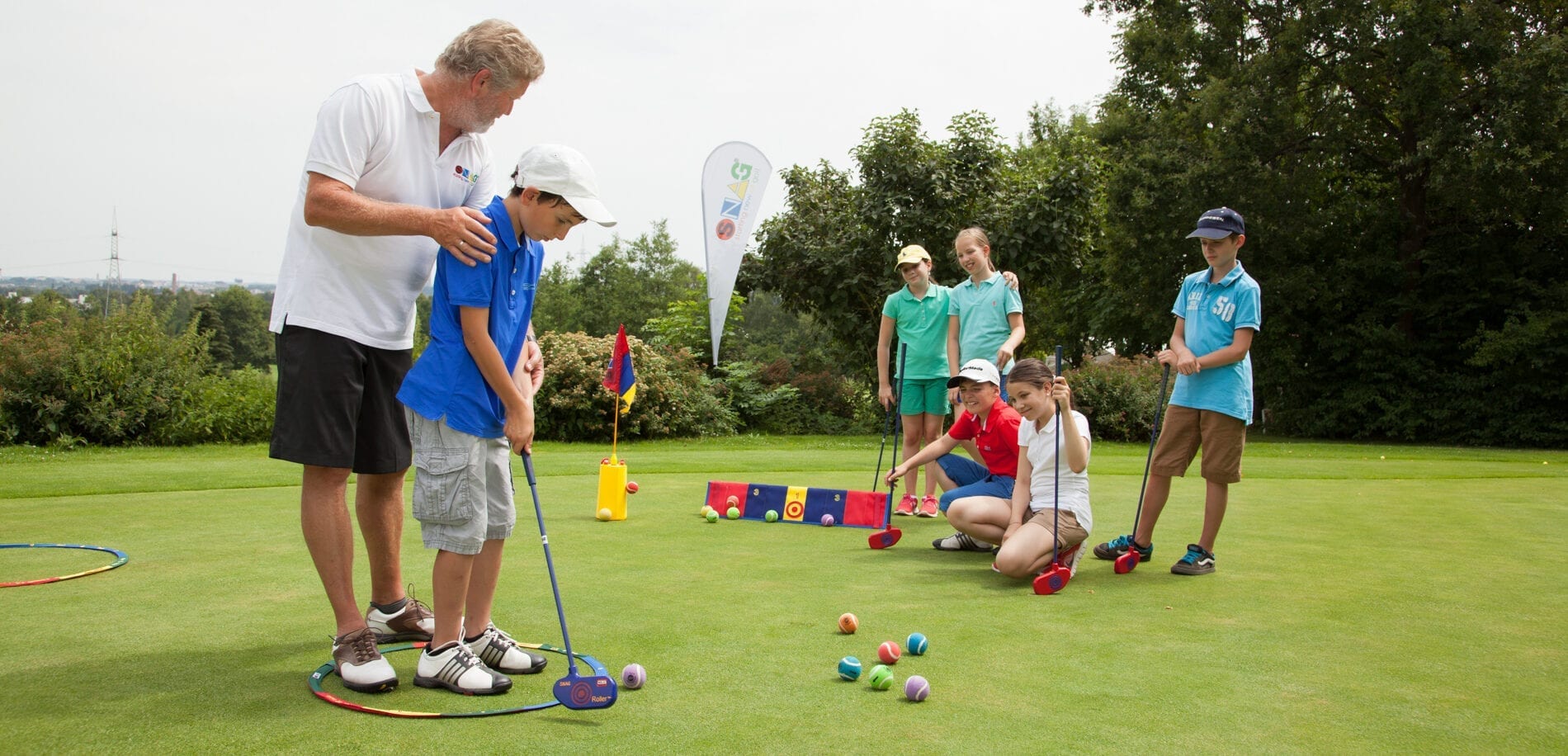 golf instructor on the course with children students