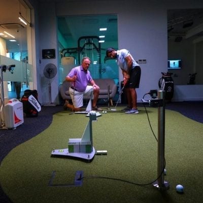 student and instructor in golf gym working on swing